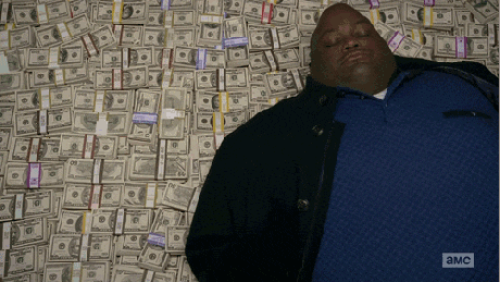 Gif shows a large man wriggling on a bed of money.