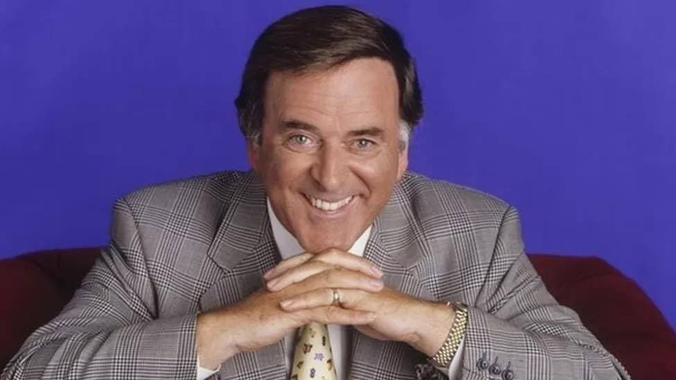A close-up shot of Terry Wogan in his 30s or 40s, smiling at the camera.