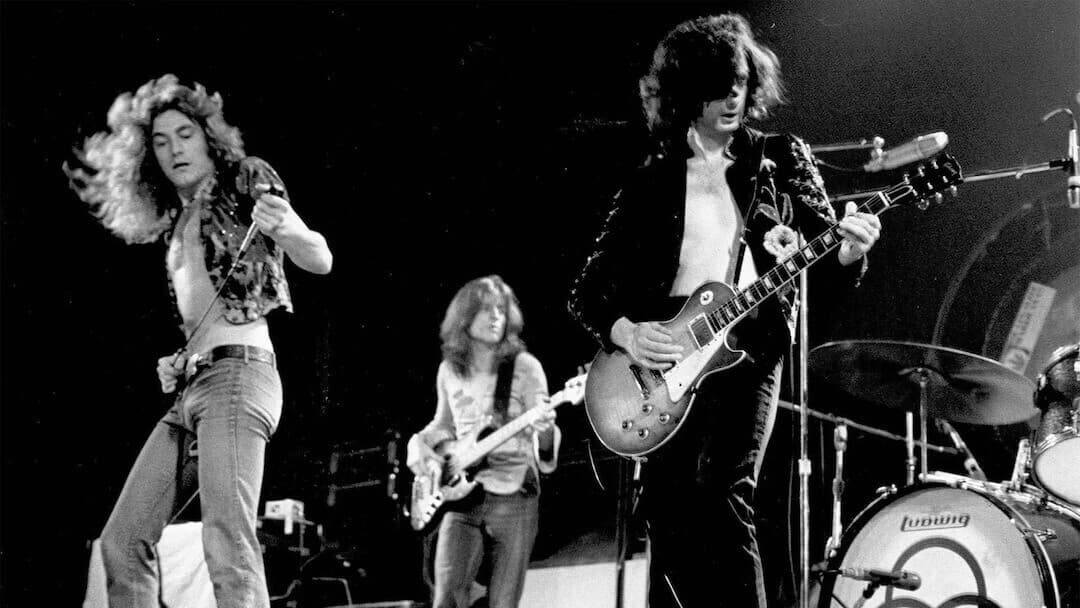 Image shows a black and white photo of Led Zeppelin on stage.