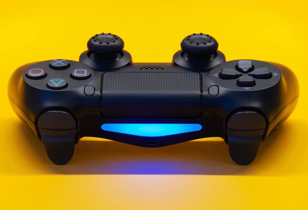 Image shows a playstation controller against a yellow background.