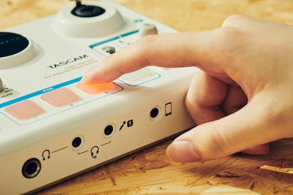 A close up of a person pushing a button on the Tascam MiniStudio Creator US-42.
