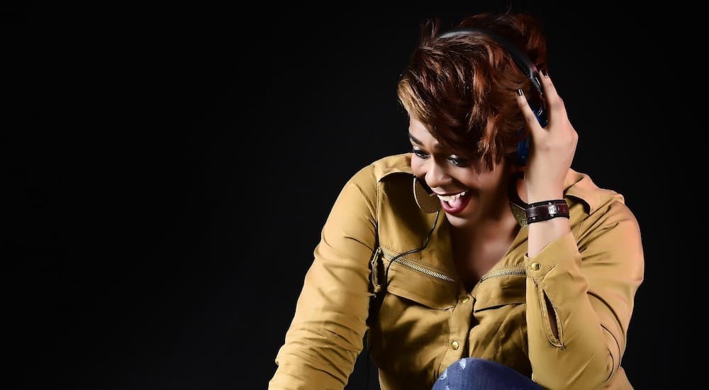 Image shows a woman laughing whilst wearing headphones.