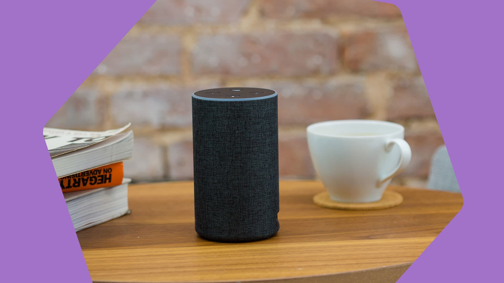 This is an image of an Amazon smart speaker Echo, a small black device with a blue ring around the top, in the cntre. On the right is a white coffee cup. On the left is the corner of some books.