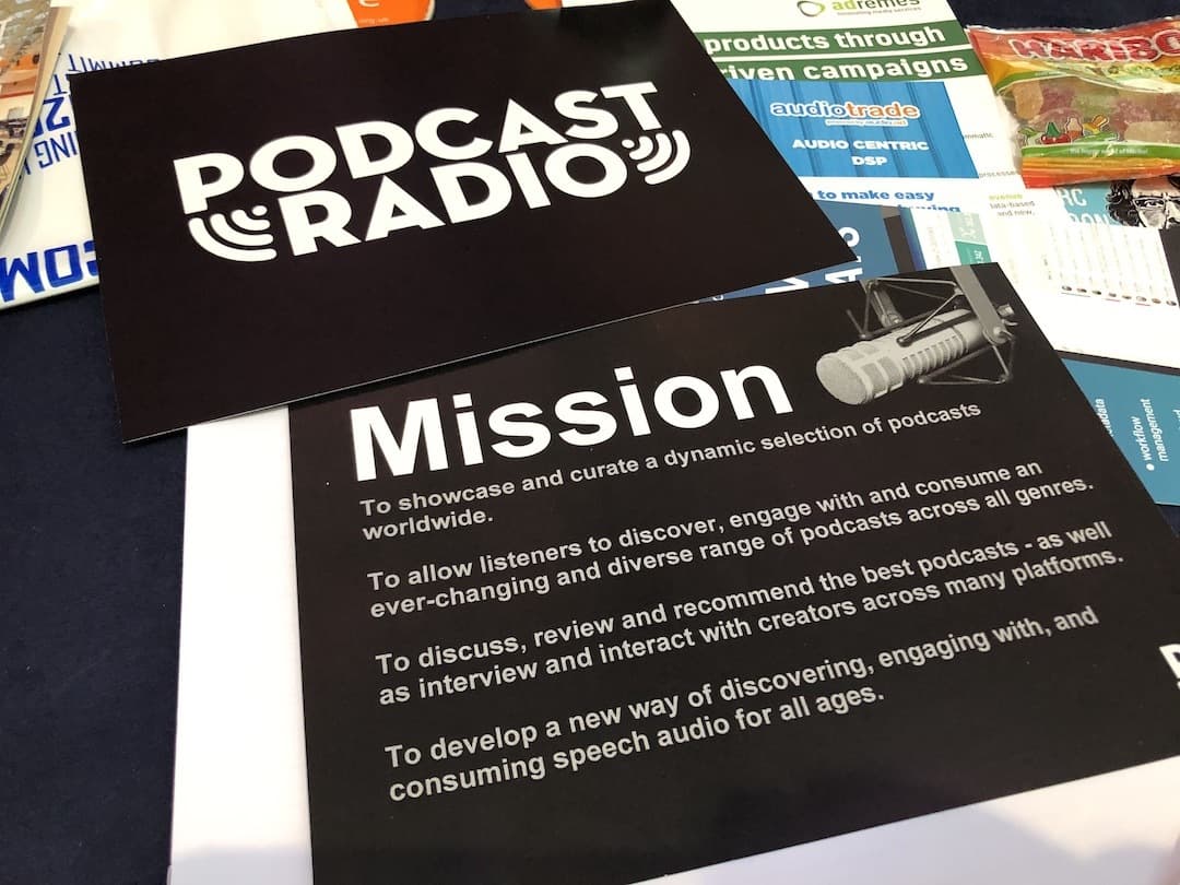 Image shows some Podcast Radio leaflets on a desk, including one that has their mission statement on it.