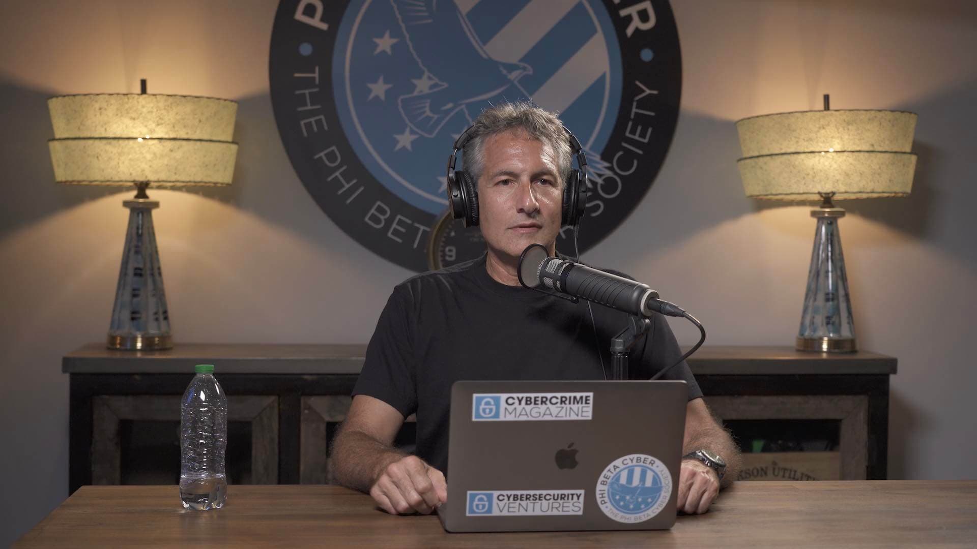 Image shows the Cybercrime Radio presenter Steve Morgan, sat behind a laptop and microphone and wearing headphones..