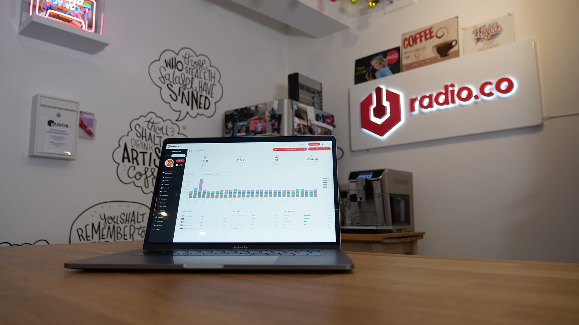 Image shows a laptop on a kitchen table. On the screen is the Radio.co dashboard showing a radio station's listener statistics.