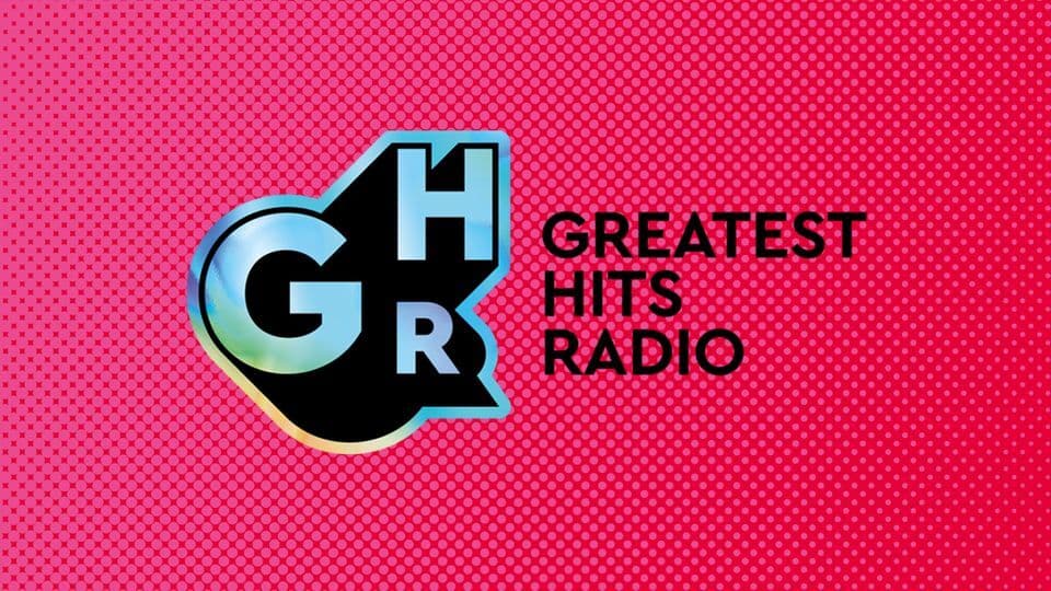 Image shows artwork for Greatest Hits Radio. It has a hot pink polka dot background and the GHR icon centre left in blue and black. "Greatest Hits Radio" is in black font, centre right.