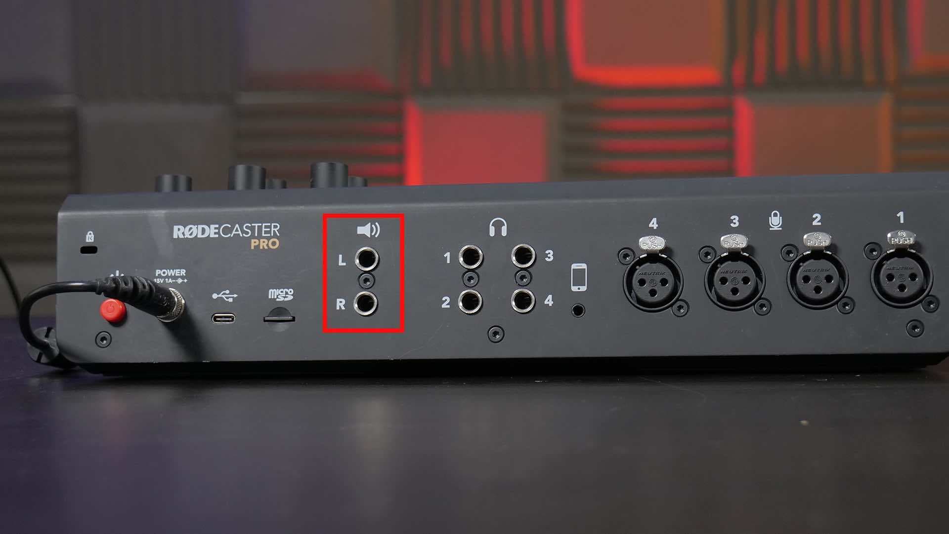 Image shows the back of a RODECaster Pro, with the speaker output port highlighted with a red square.