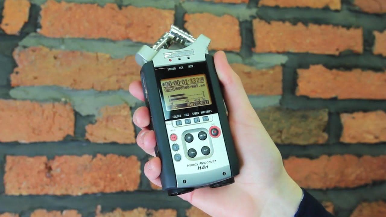 A hand holding the H4N hand-held recorder, against a brick wall.