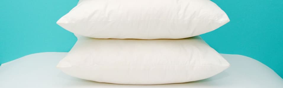 Image shows a stack of pillows against a blue background.