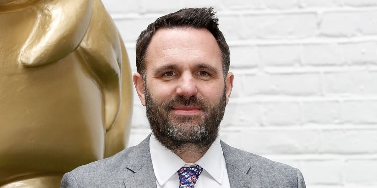 A close-up photo of Shaun Keaveny wearing a suit at an event.