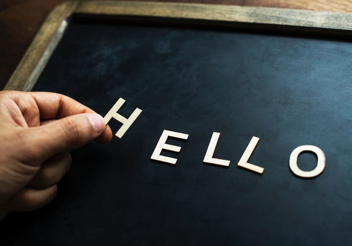 Image shows someone placing cut out letters to spell 'hello' on a chalk board.