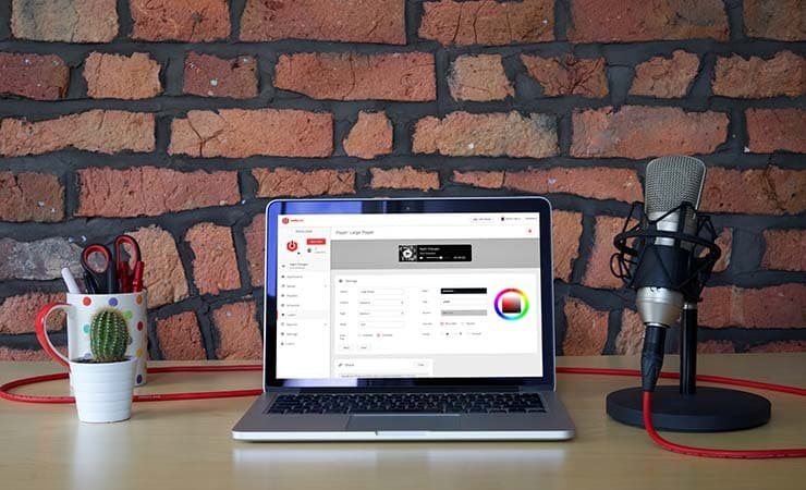 Image shows a laptop and microphone on a desk.