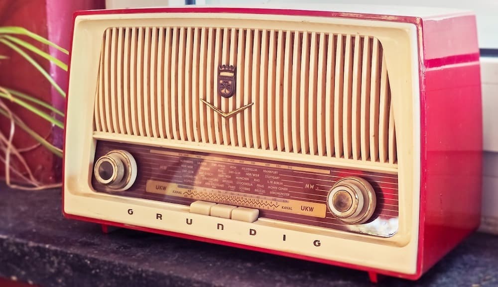 Image shows a red, retro Grundig radio on a table.