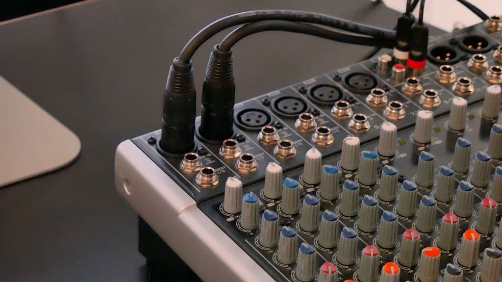 Image shows a close-up of a mixing desk that has 2 XLR cables plugged into it.