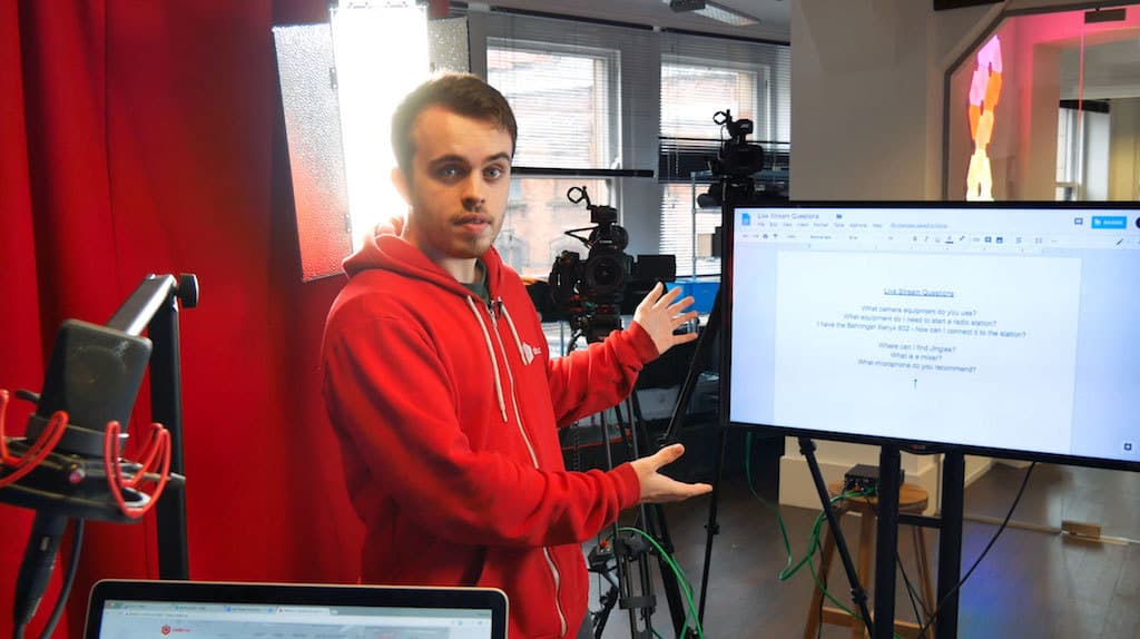 Image shows a man pointing to a screen where there is a google drive document on it.