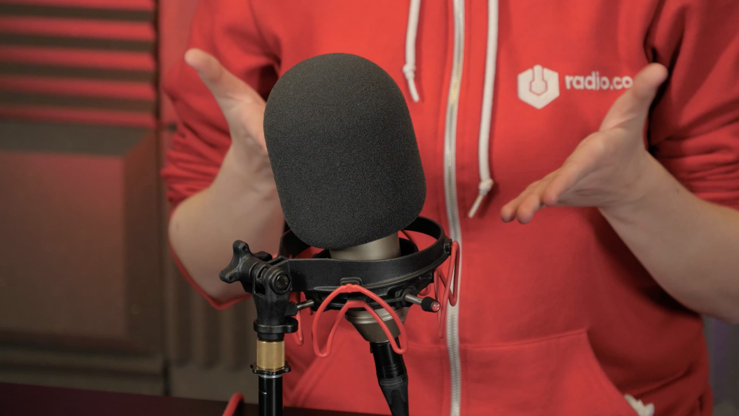 Image is a close up of someone showing the Behringer B-1 Microphone with their hands in a studio.