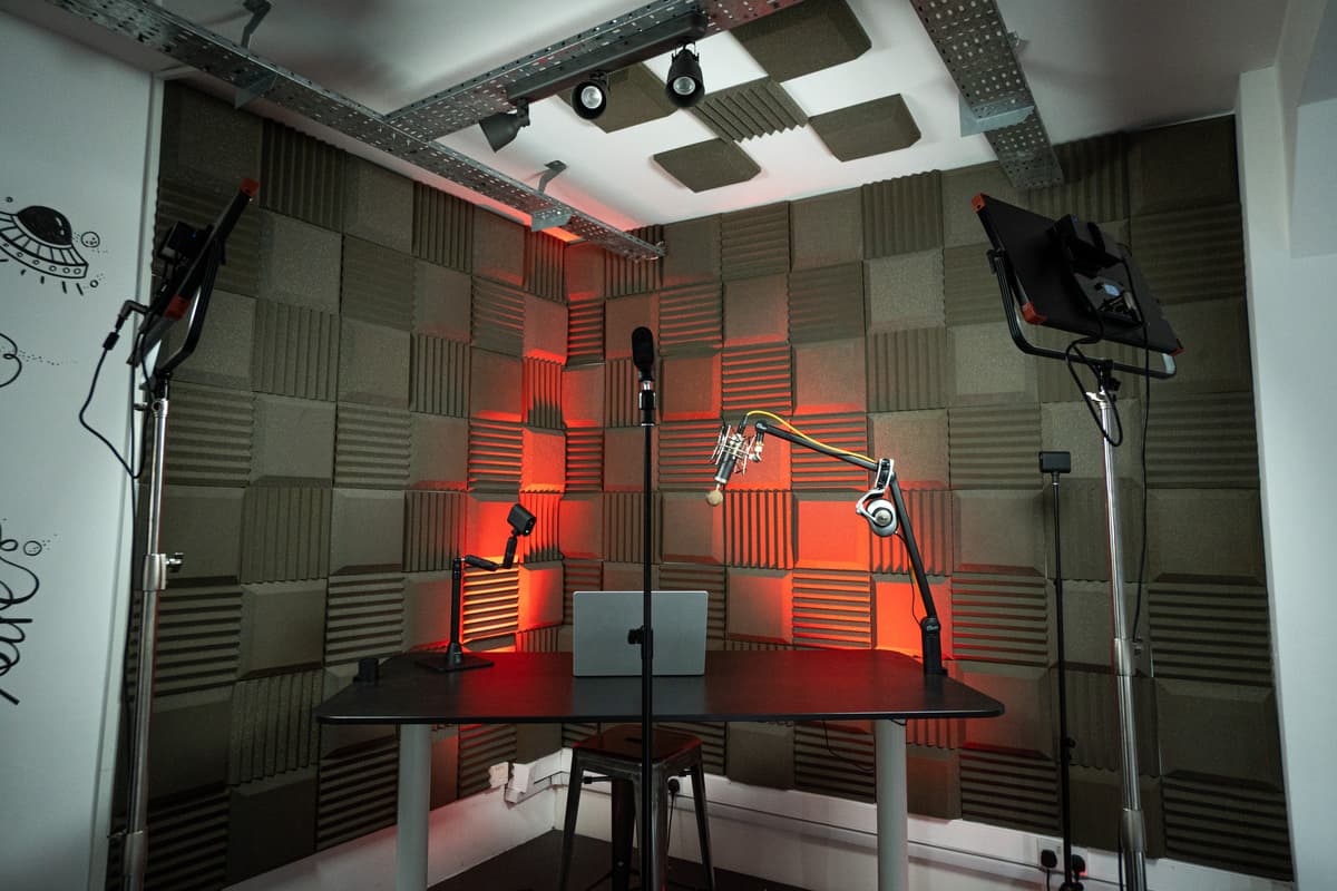 A professional streaming set up that has 3 Mevo cameras and professional standing lights pointing towards the laptop and table in the centre of the booth.