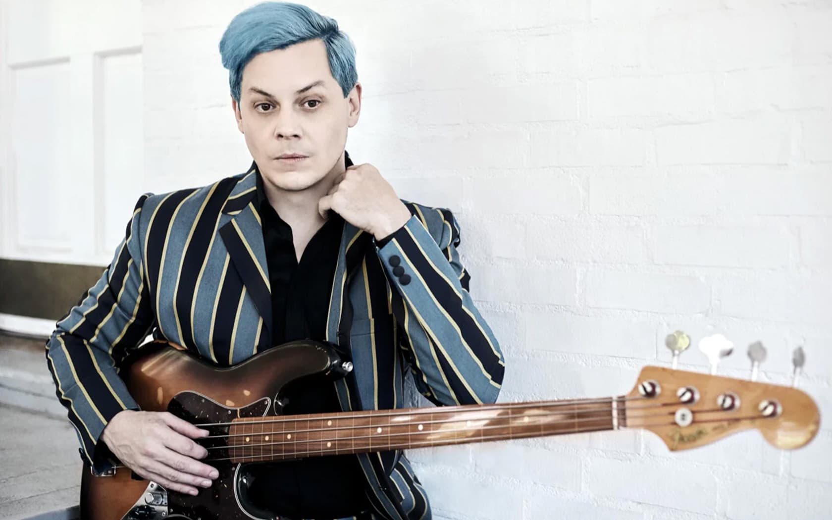 Image shows the musician Jack White, holding a guitar and looking