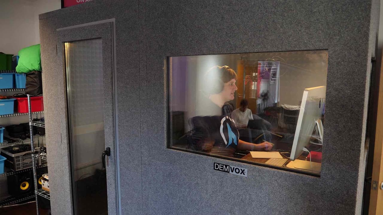 Image shows a person broadcasting within a purpose-built sound booth