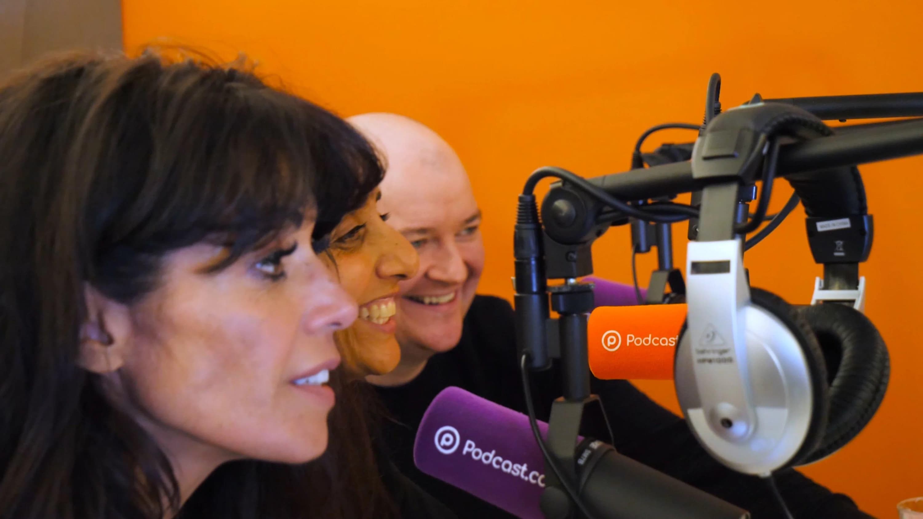 Image shows three people sitting side by side and speaking into radio microphones.