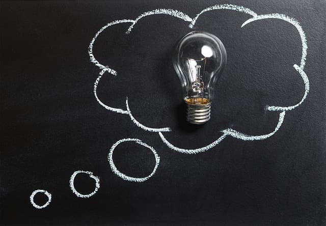 Image shows a thought bubble drawn on a chalkboard and inside the thought bubble a lightbulb has been placed.