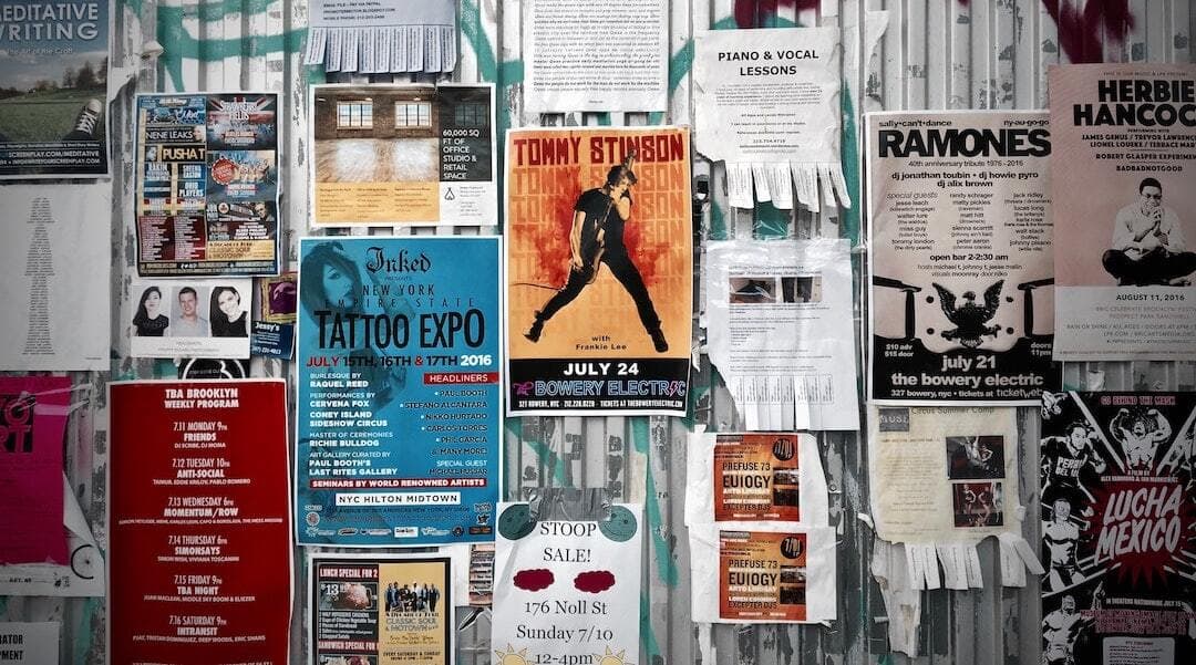 This is a picture of a heavily postered/flyered wall. There are posters of all different colours and covers.