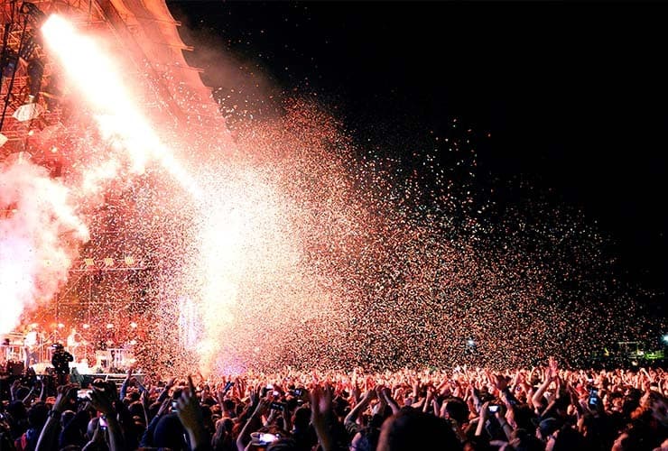 A crowd cheering a band at the Primavera Sound Festival with confetti in the air.