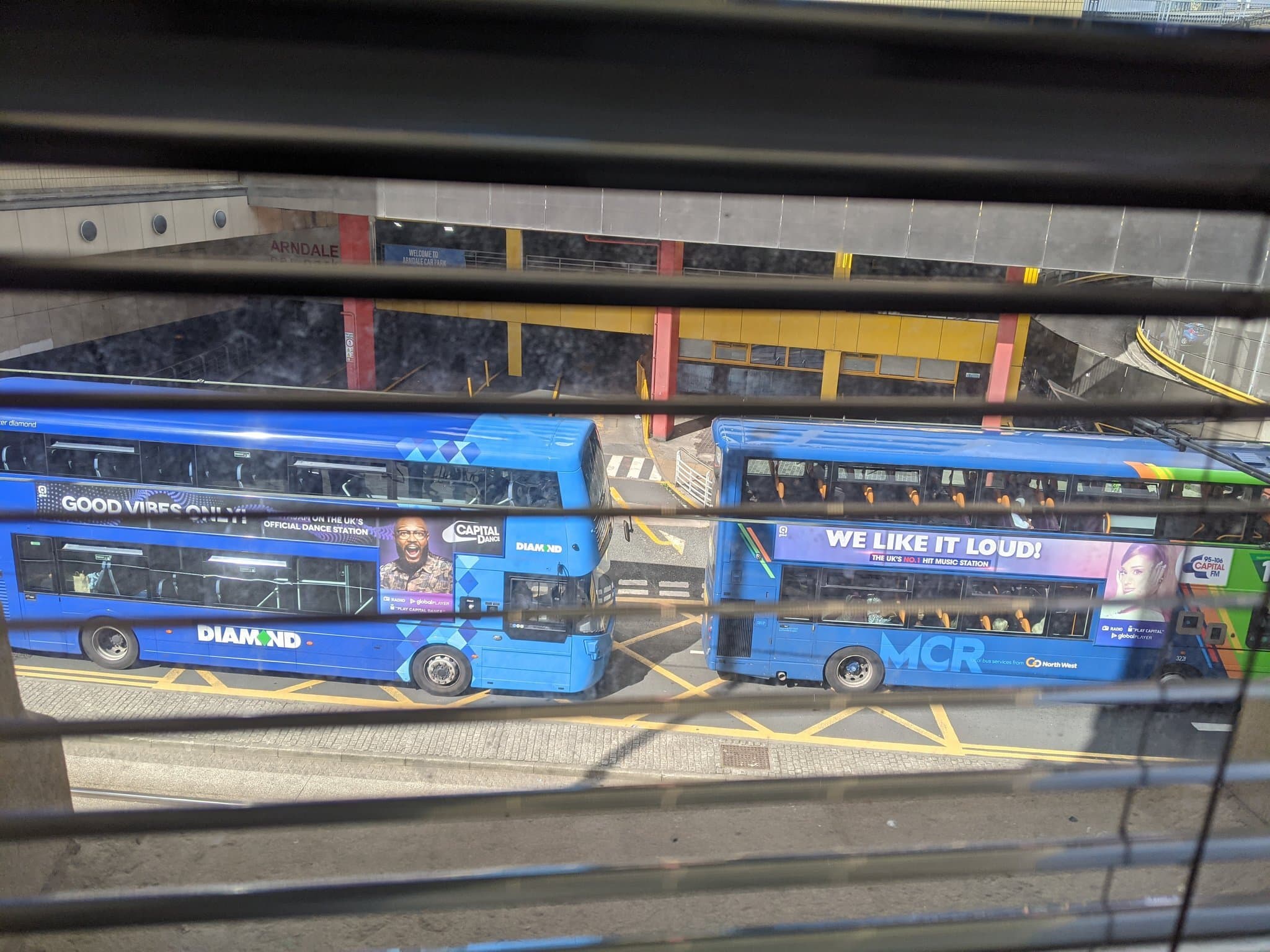 Image shows two buses in the UK, with radio advertisements on their sides.