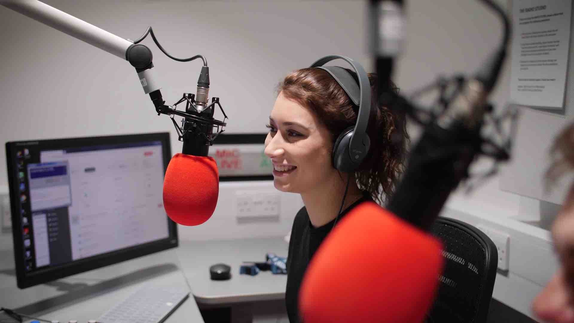 Image shows a woman presenting a radio show in a radio studio