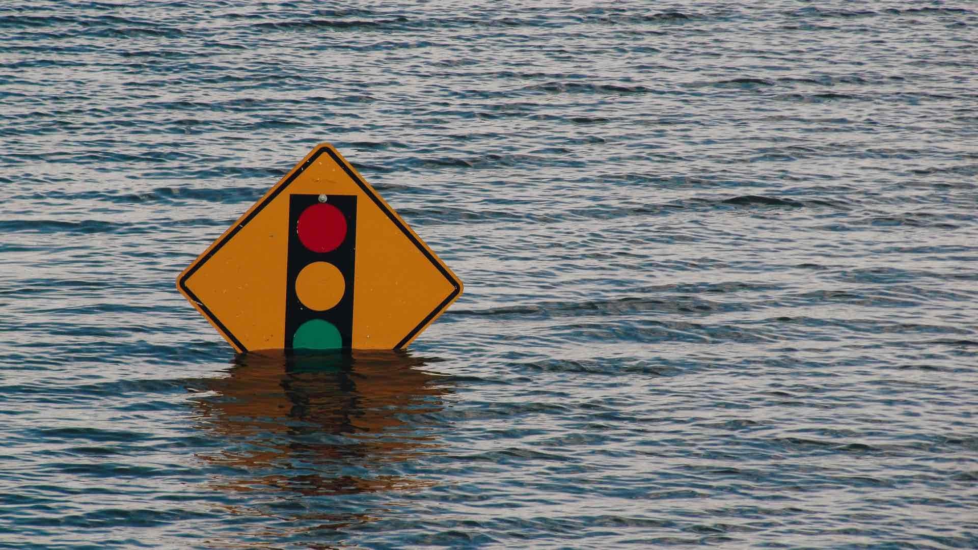 An American traffic lights sign partly submerged in water.