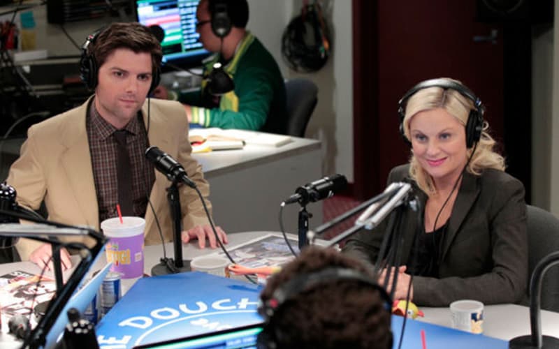 Image shows the Parks and Recreation characters Lesley and Ben being interviewed on the Crazy Ira and The Douche radio show.