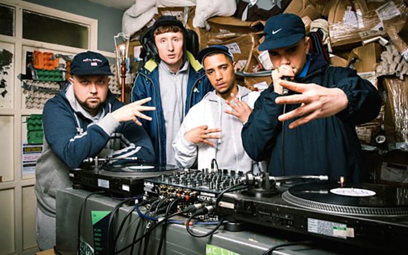 Image shows the Kurupt FM gang posing for the camera in their pirate radio studio.