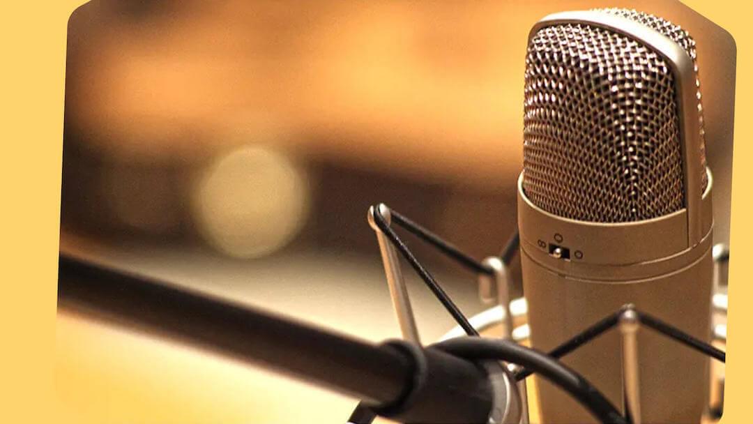 With yellow borders, this image shows a silver microphone and black stand against a neutral warm background.