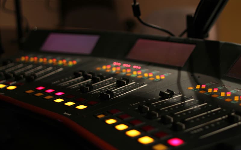 Image shows a lit up broadcasting desk within a radio studio.