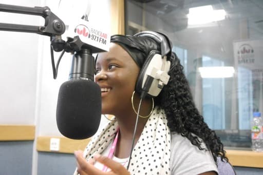 A woman talking in to a microphone in a radio booth.
