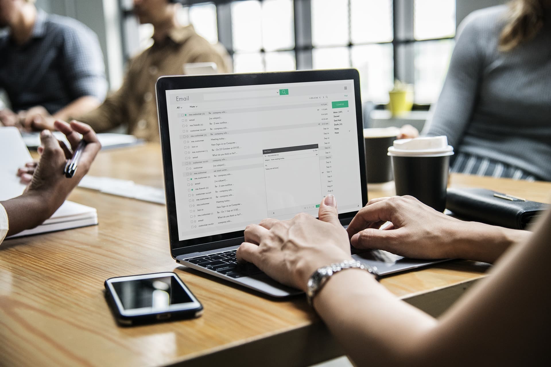 Image is a close-up of a woman's laptop while she's in a business meeting.