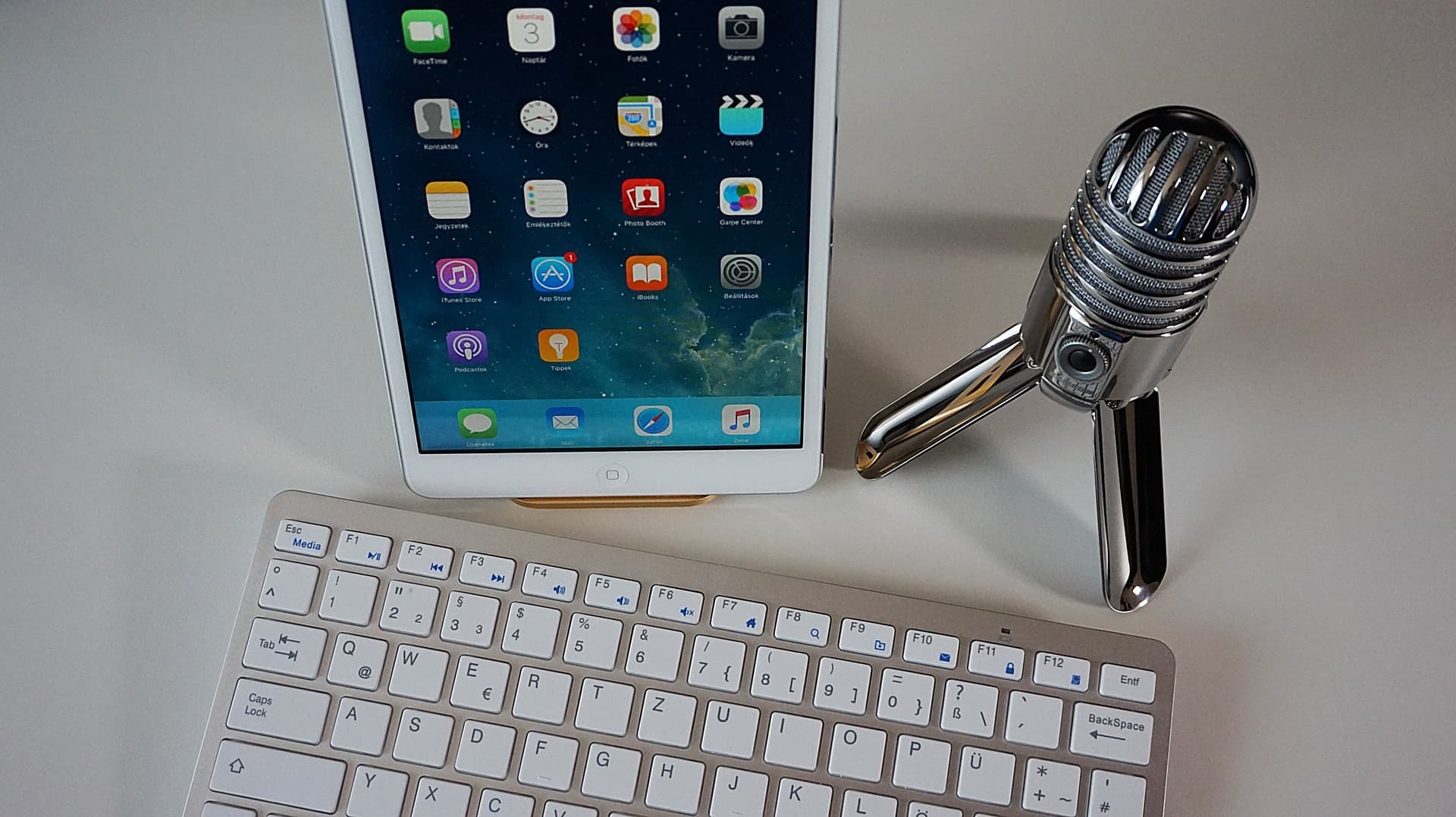 Image shows a keyboard, iPad and microphone on a desk.