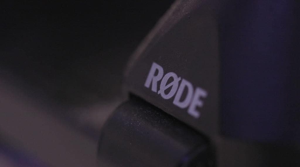 This is a black zoomed in image of a Rode PSA1 Boom Arm, with just the white RODE logo visible.