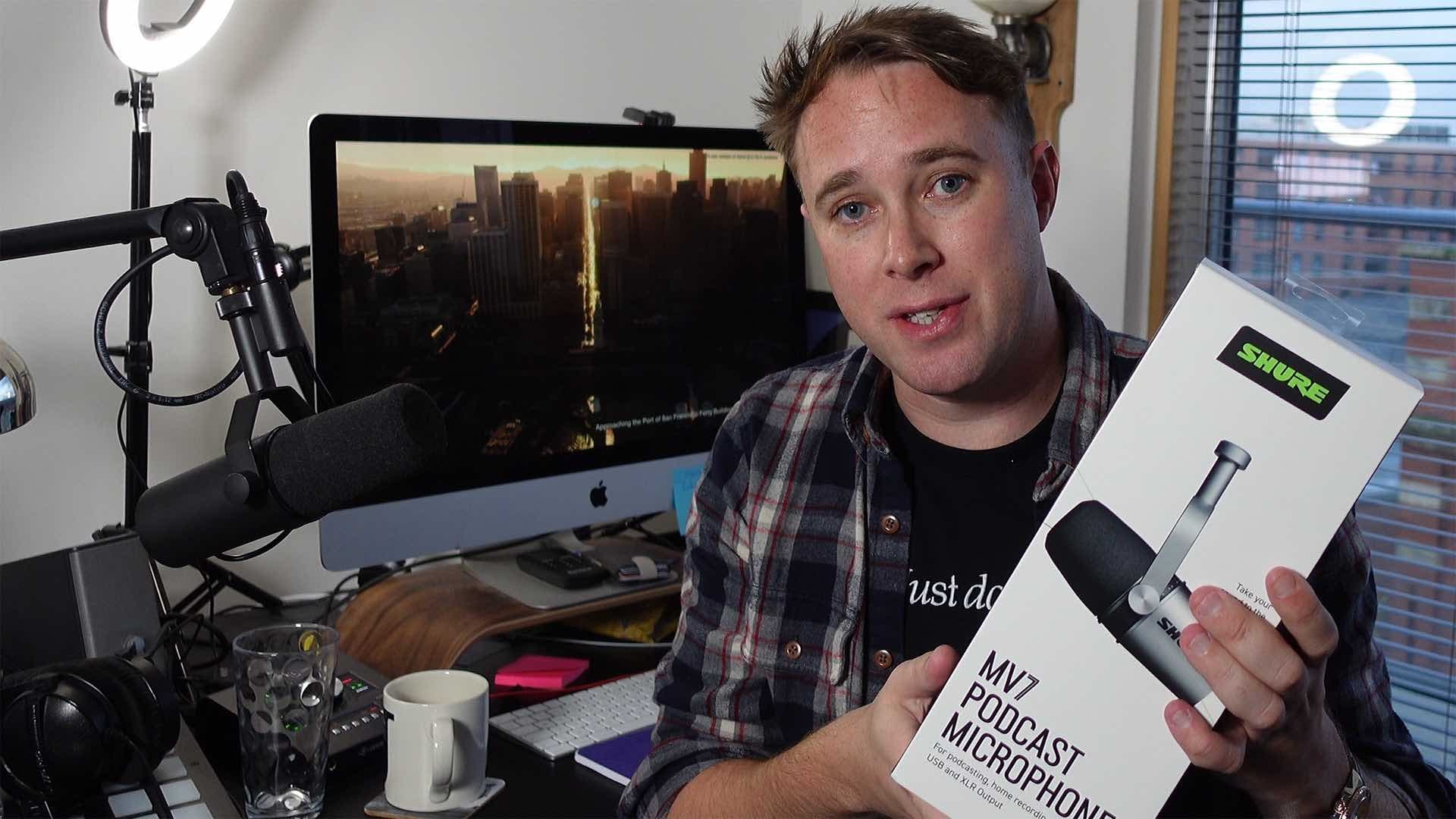 Image shows Radio.co CEO, James Mulvany, holding the Shure MV7 box in his home studio.