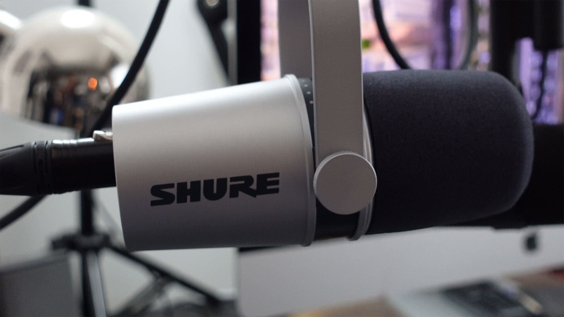 Image shows a silver Shure MV7, suspended from a boom arm and with an XLR cable plugged into it.