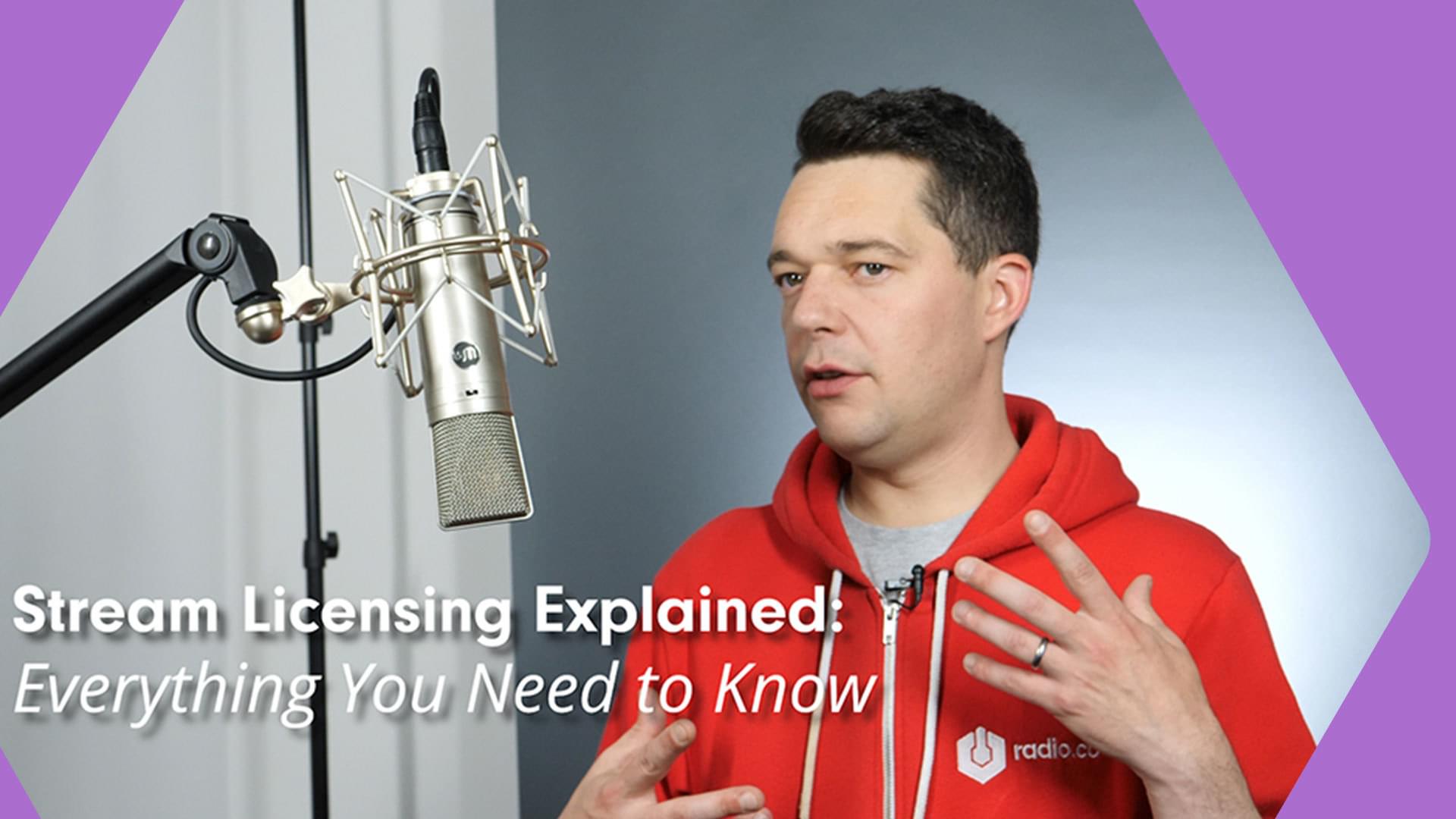 A white man with dark hair in a red hoodie presents to a microphone on a stand in front of him. His hand is raised to gesticulate. There are purple borders to the image, and a caption of 'Stream Licensing Explained'.