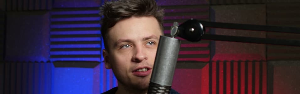 Image shows a young man behind a microphone in a soundproofed room.