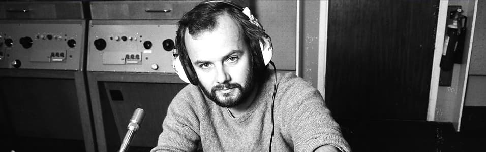 Image shows a black and white photo of a young John Peel in a radio booth.