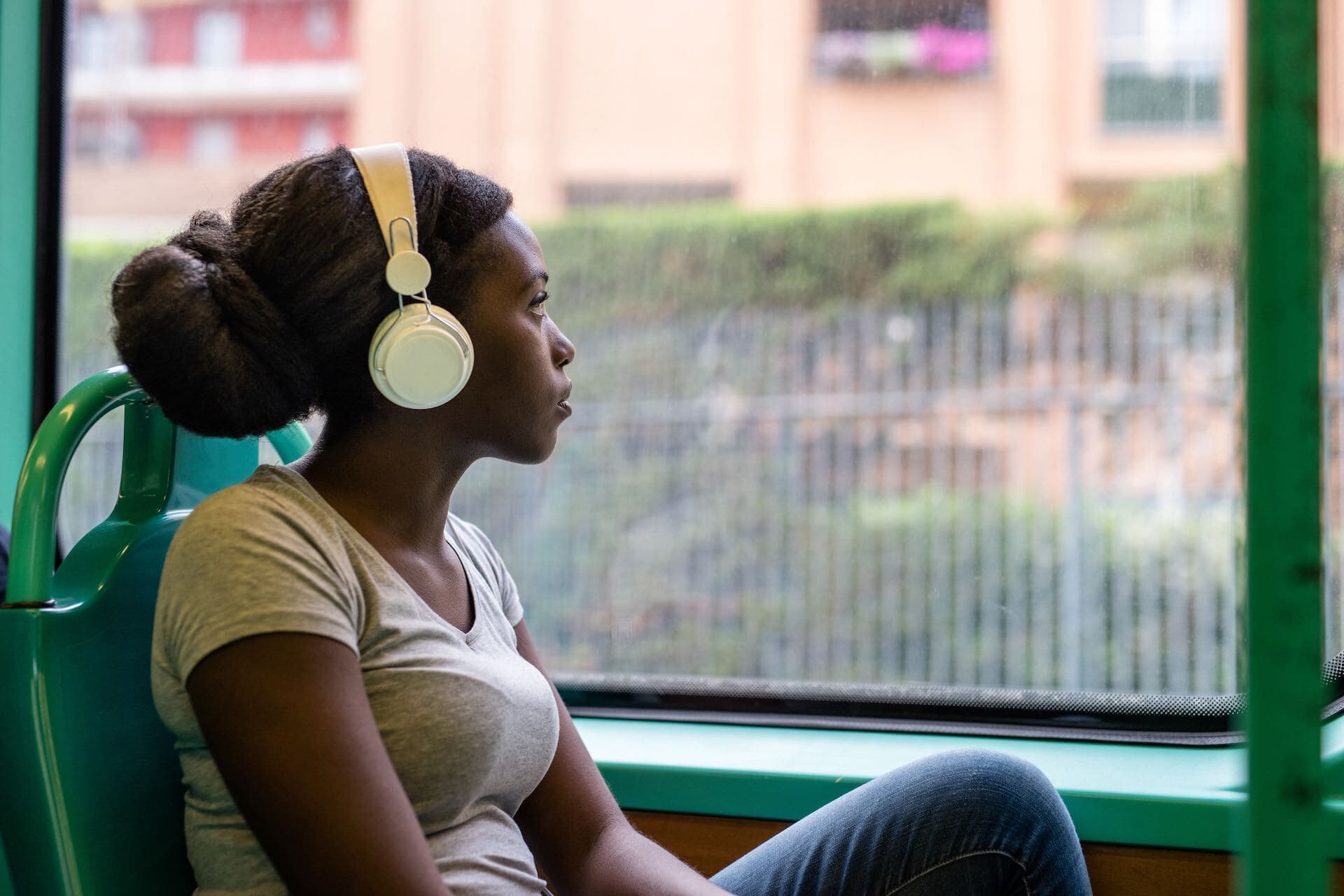 Woman listening on a pair of headphones whilst travelling.