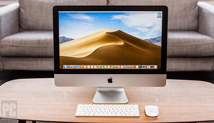 Image shows an Apple iMac Computer, keyboard and mouse, placed on a coffee table.