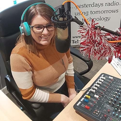 Image shows a woman behind the microphone at the Lake District Radio studio.