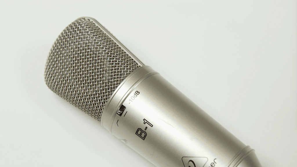 Image shows a close-up of a Behringer B1 microphone, laid flat on a desk.