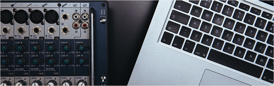 This is an image of a black sound mixer on the left. On the right touching it are the keys of a Macbook, black contrasting onto a silver back.