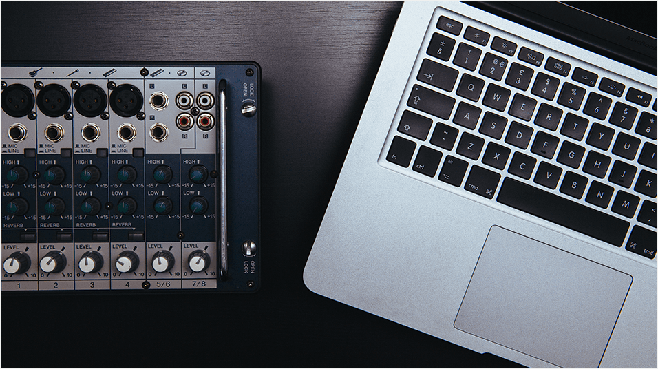 Image is a birdseye view of a mixer and laptop on a desk.